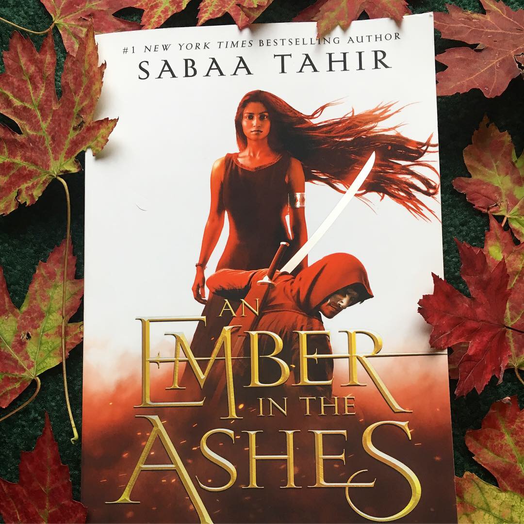 An Ember in the Ashes by Sabaa Tahir surround by red maple leaves