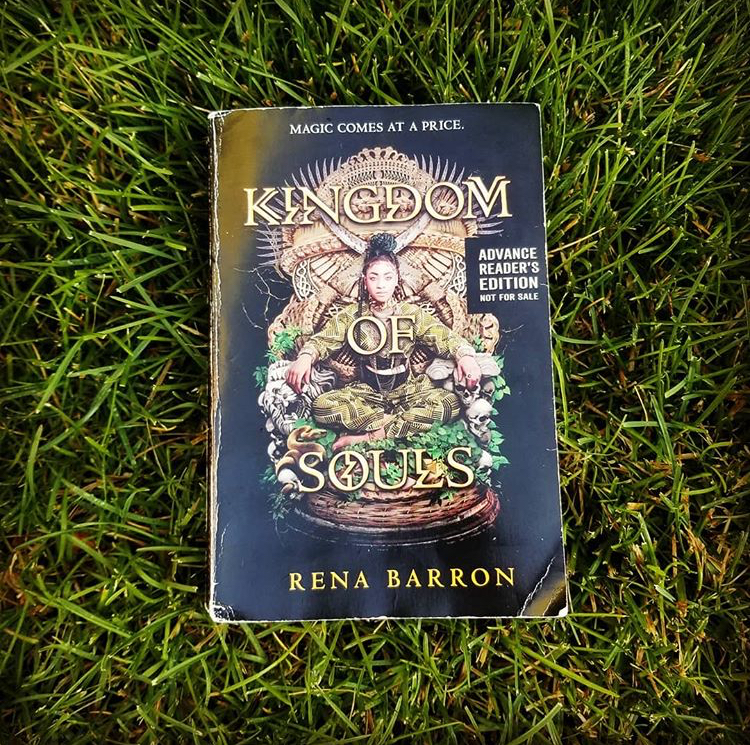 Paperback version of Rena Barron's KINGDOM OF SOULS lies on bright green grass