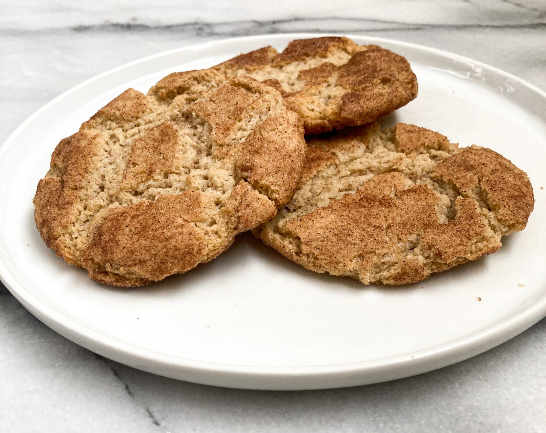 Three snickerdoodle cookies stacked on a white plate