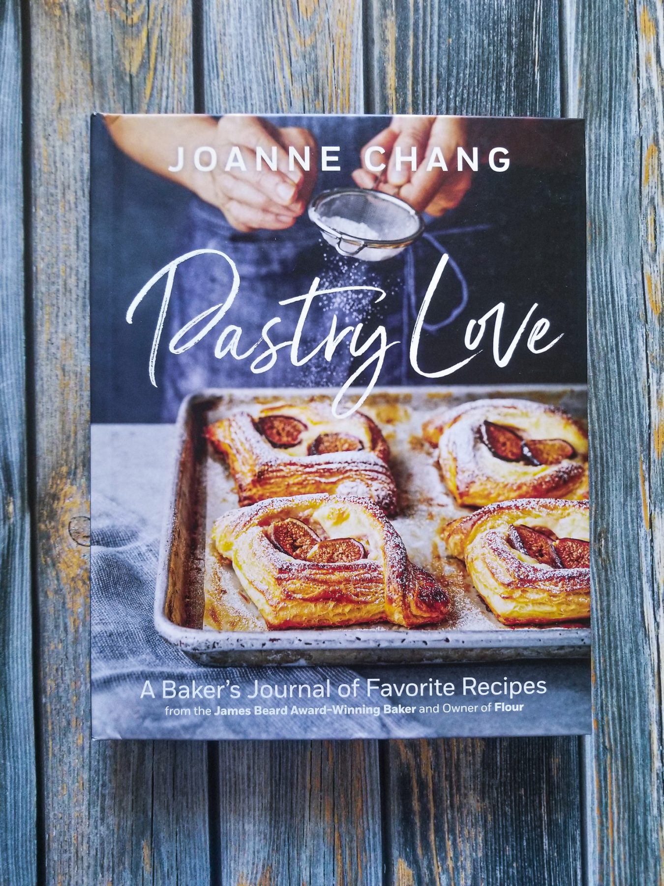 hardcover of Joanne Chang's PASTRY LOVE lays on top of a wood plank background