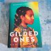 book, The Gilded Ones by Namina Forna on a blueish grey background